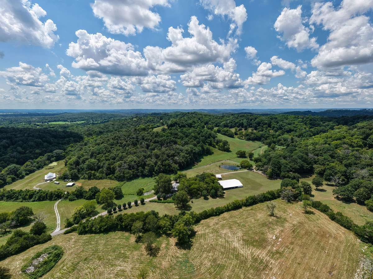 Expansive aerial view highlighting the historic farmhouse, pavilion, pond, barns and surrounding open fields—illustrating the scale and versatility of this 164± acre estate.