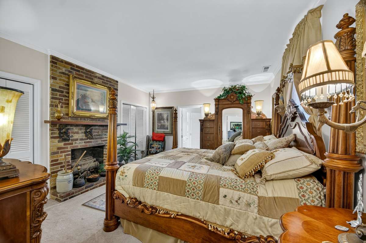 Main-level guest bedroom with brick fireplace, comfortable proportions, and flexible layout for guest accommodations; furnishings may be included, partially included, or removed based on buyer preference.