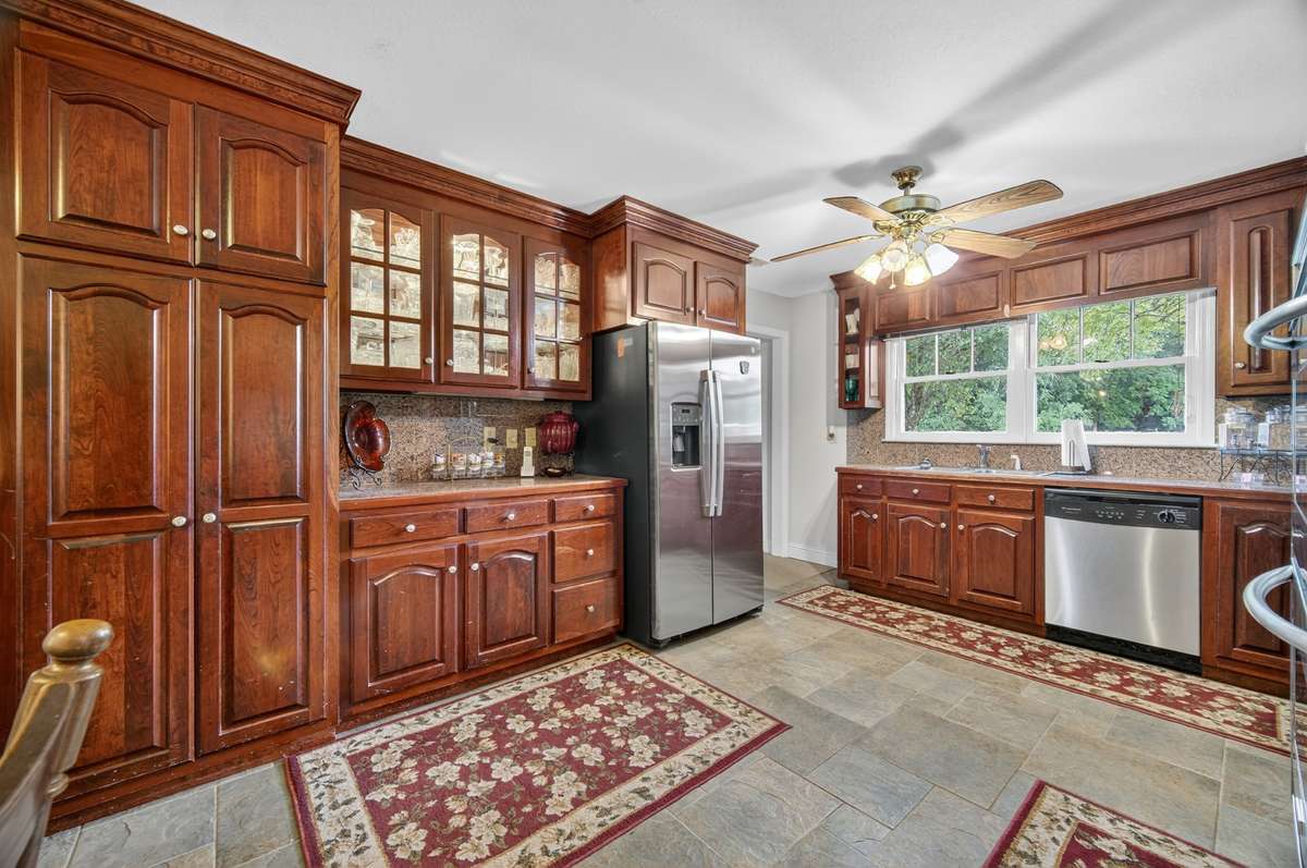 Alternate kitchen view highlighting extensive cabinetry, generous counter space, and efficient layout with natural light; furnishings may be included, partially included, or removed based on buyer preference.