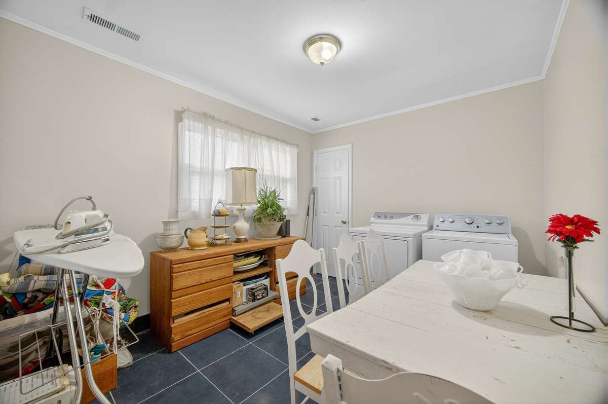 Spacious laundry and utility room with washer and dryer, offering flexible space for household needs, event preparation, or estate operations.