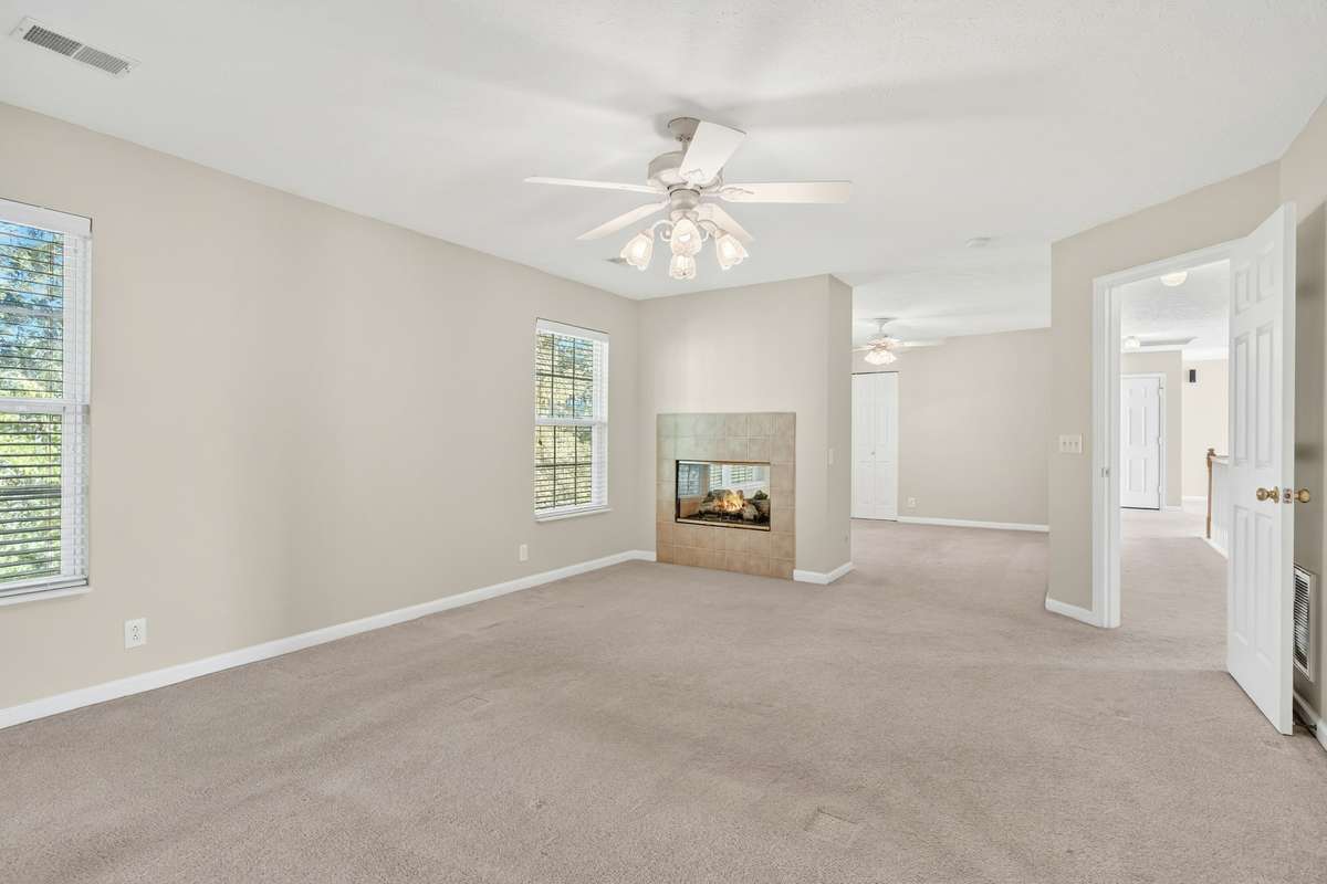 Primary suite view into its own private sitting room and double-sided fireplace with gas logs
