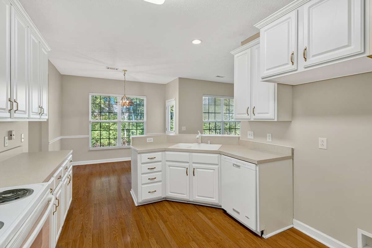 Kitchen with white cabinets and wood floors. . .  home is in move-in condition with all new neutral paint!