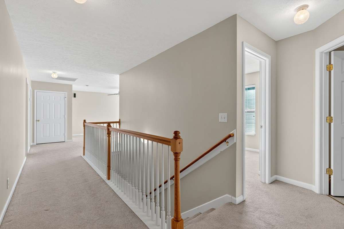 Upstairs hallway leads to open bonus room on one end and primary bedroom on the other end.  Smooth ceilings in entire home