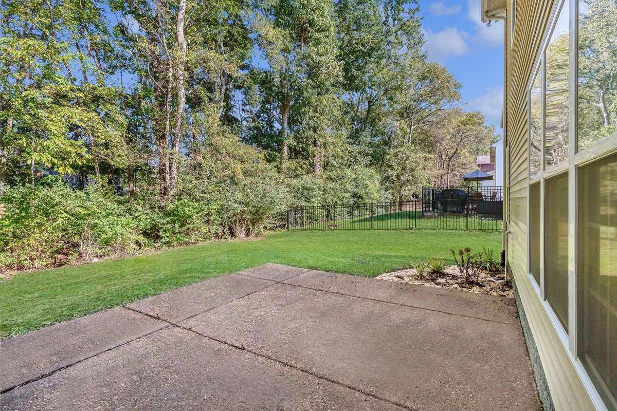 Large outdoor aggregate patio overlooks mature trees . . .for wonderful privacy.  (Photo virtually brightened)