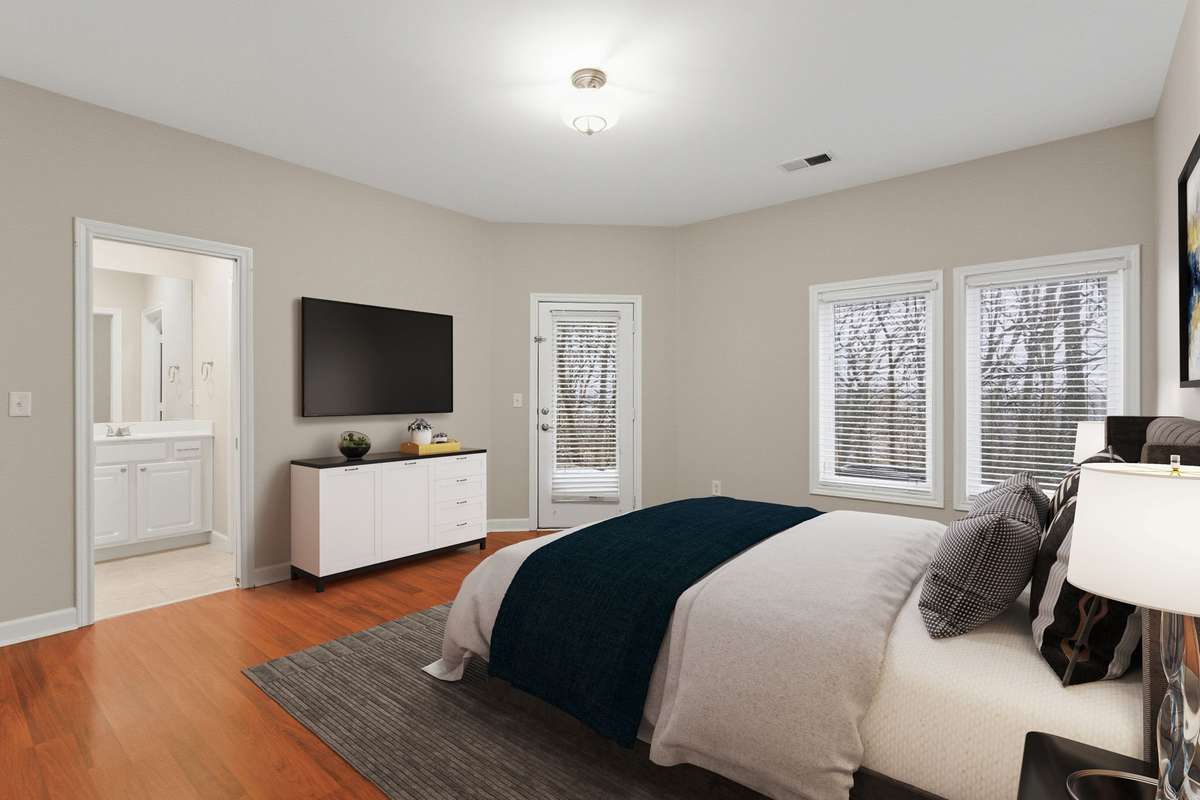 The large lower-level second bedroom offers a private en-suite bath, ample closet space, and a private door leading to the covered back porch. (Virtually staged.)