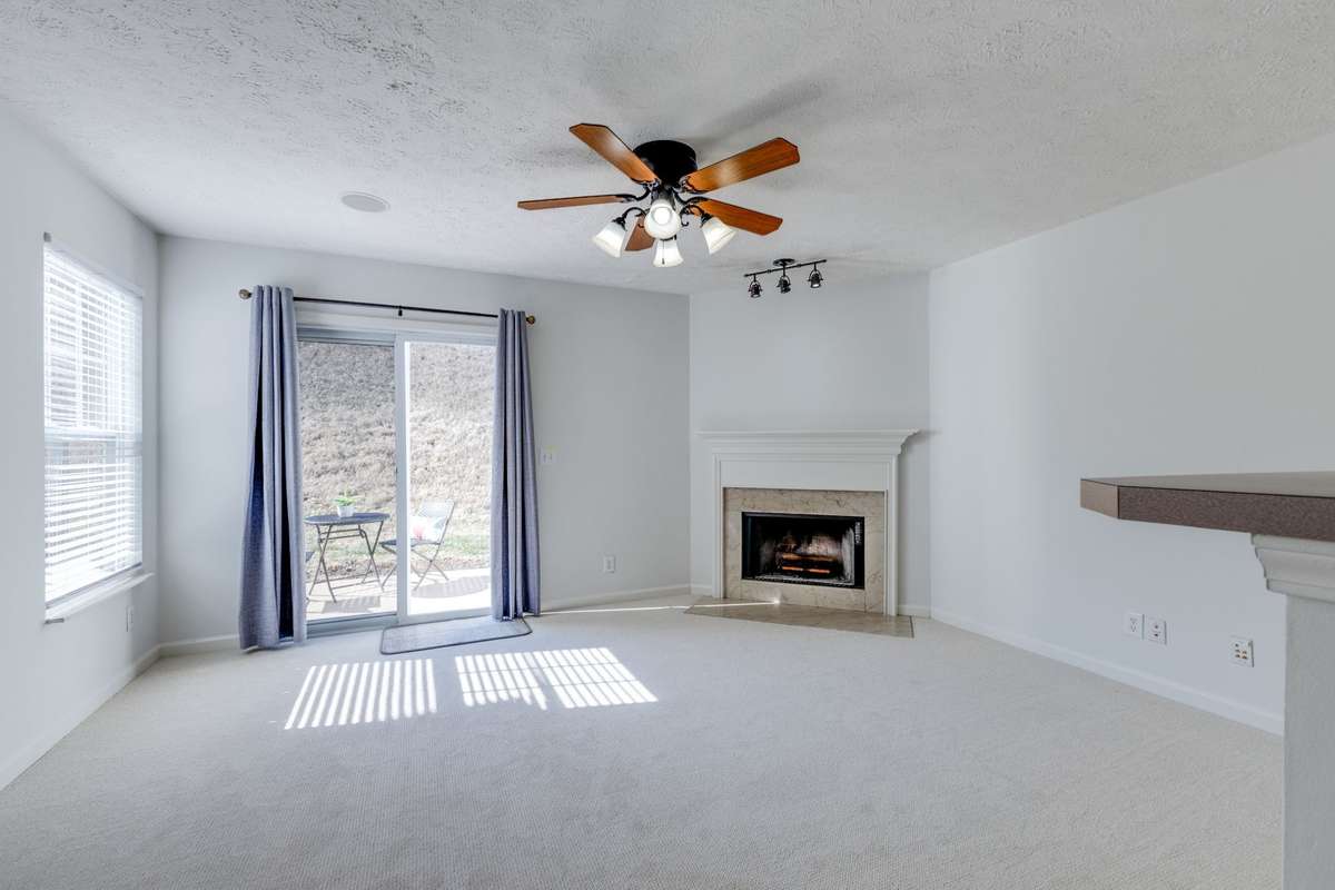 At the back of the home is the large living room with lovely natural light - extra windows for the end unit. There are two surround sound speakers, a wood burning fireplace and sliders onto your private patio.