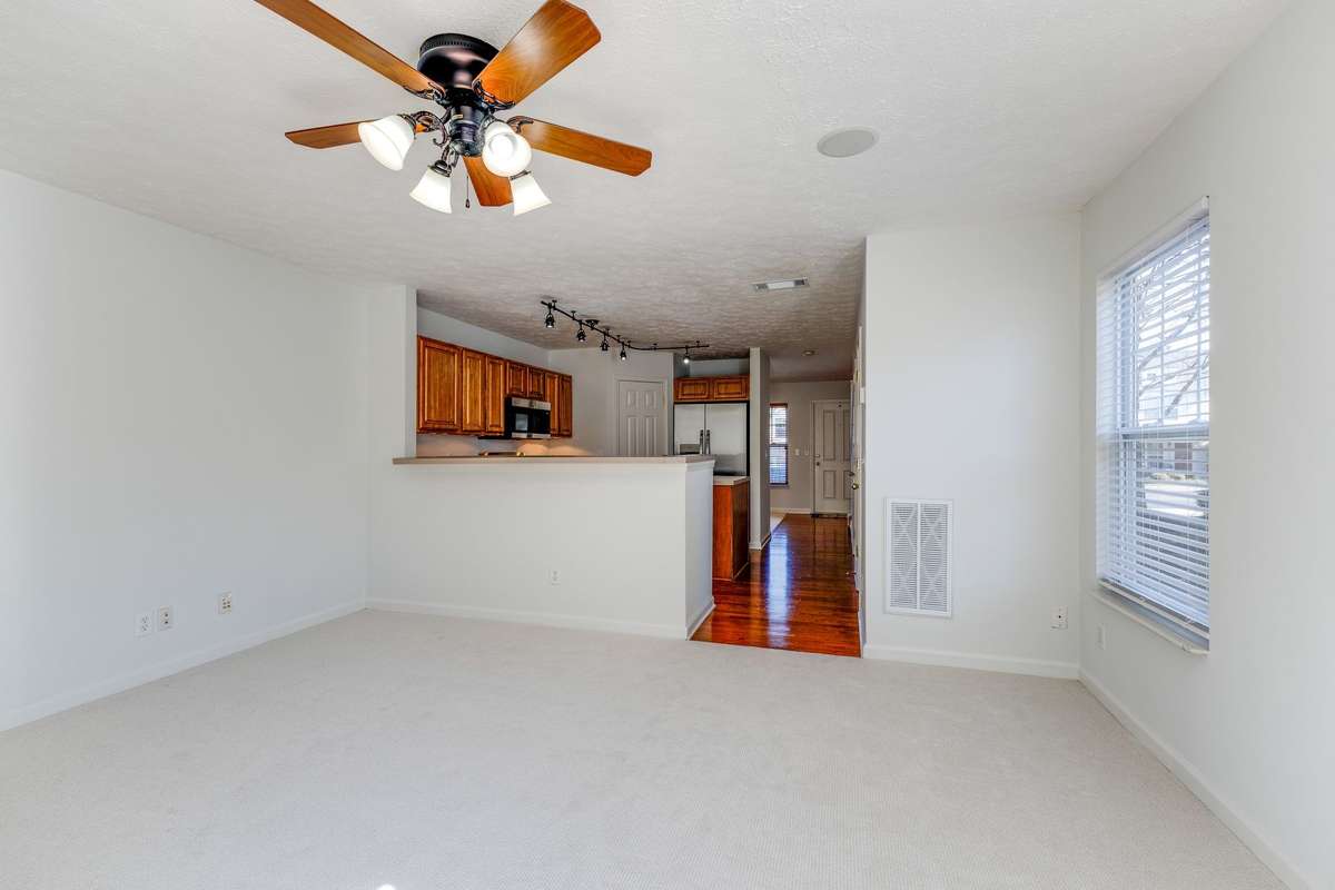 The living room features new blinds, new carpet and a Hunter Douglas fan.