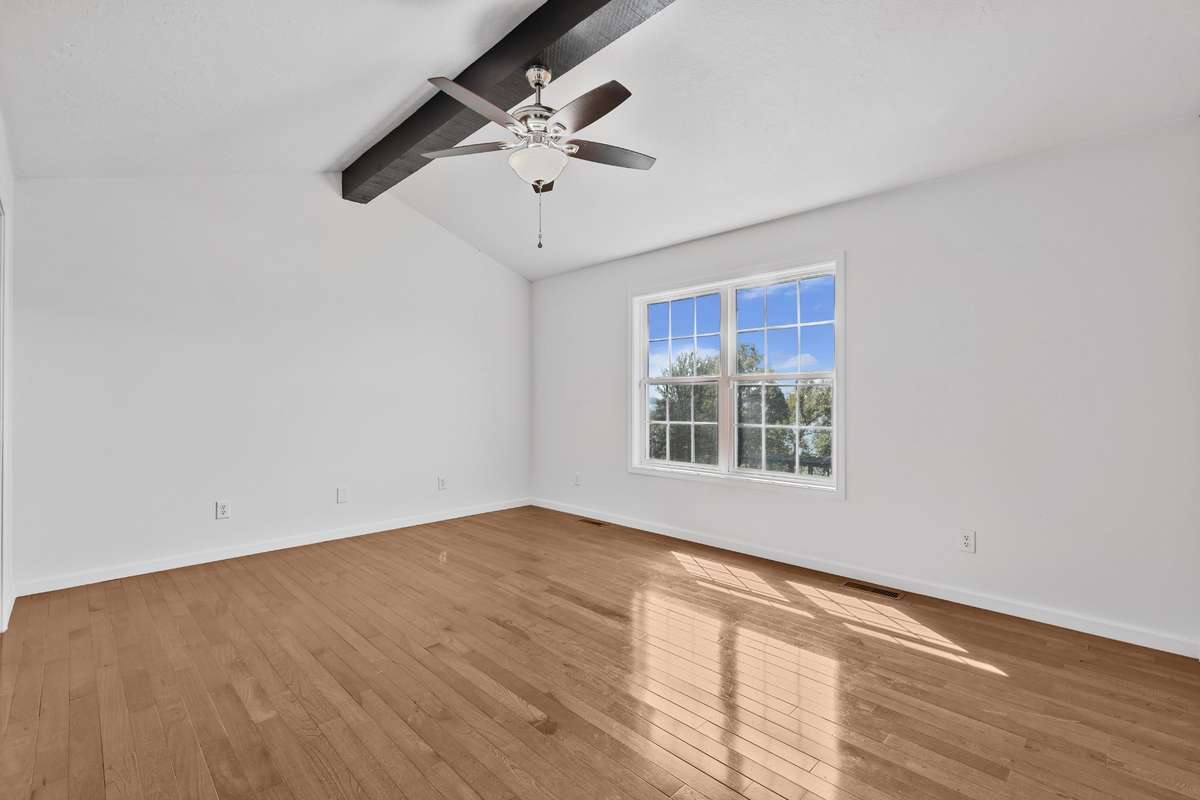 Upstairs primary suite exposed beam and hardwood flooring