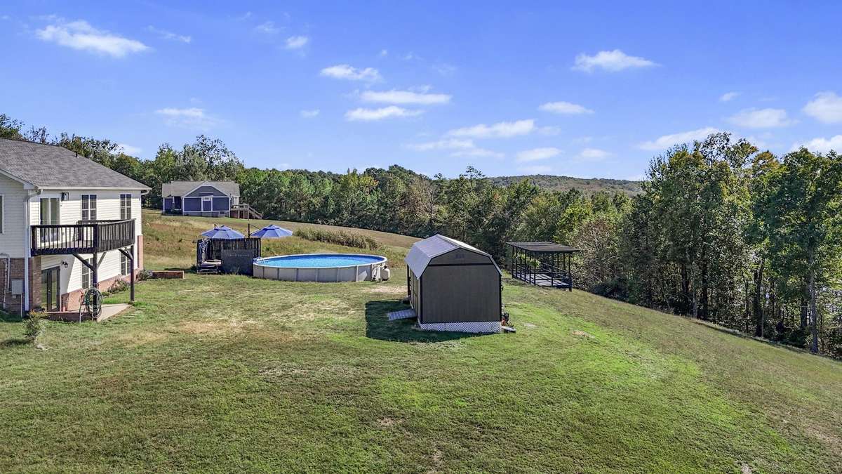 Expansive backyard offering privacy, pool, and storage shed.