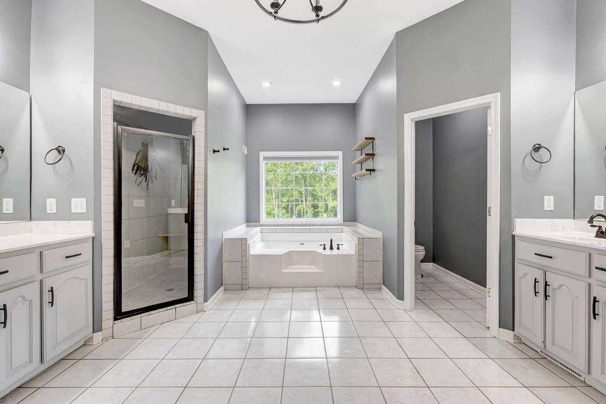 Primary Bathroom 1 featuring a soaking tub, walk-in shower, water closet, and double walk-in closets
