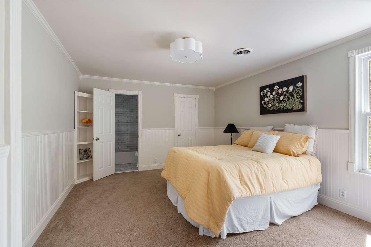 This large bedroom is full of character with classic wainscoting, a corner built-in, and a stylish light fixture.