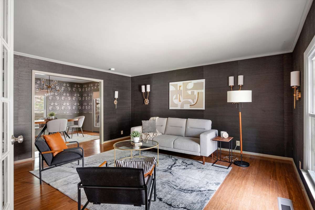 Seamlessly connected to the dining room, this moody space flows beautifully into a stunning setting with designer wallpaper and a statement light fixture.