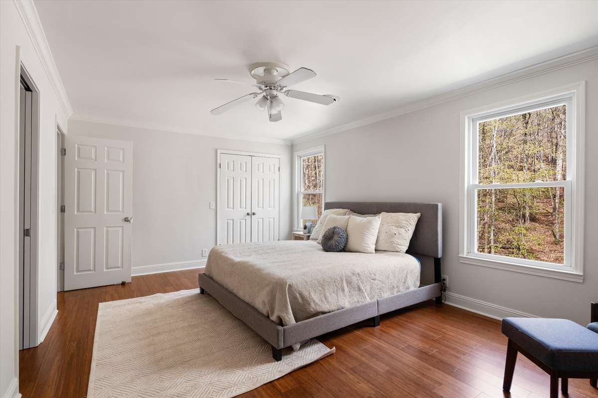 A generously sized bedroom with great natural light and a walk-in closet featuring a built-in storage system.