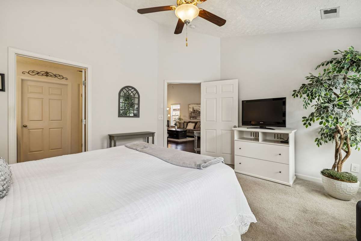 Primary bedroom with carpet & vaulted ceilings