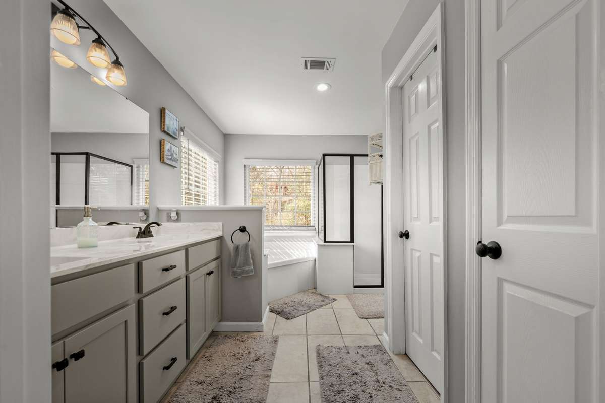 Expansive Primary bathroom complete with His/Hers Closets!   Recently updated with new tile, double vanities and glass shower encloser