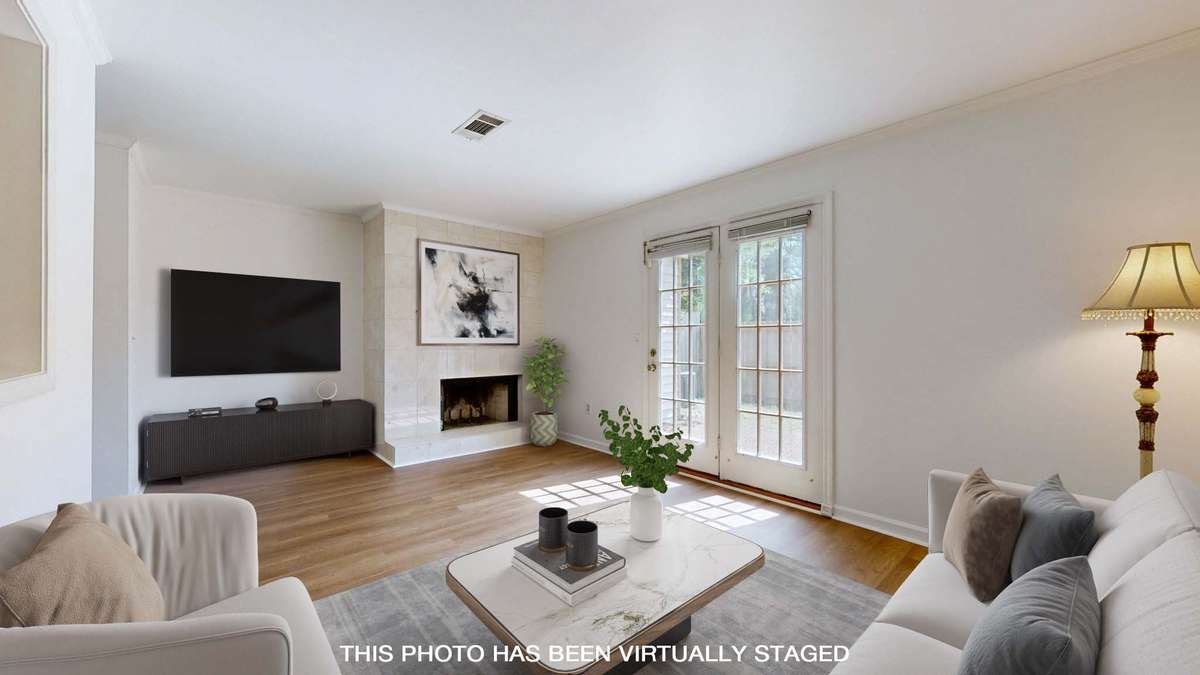 Relaxing great room space with new luxury vinyl plank flooring, crown molding, fireplace and access to the back patio.