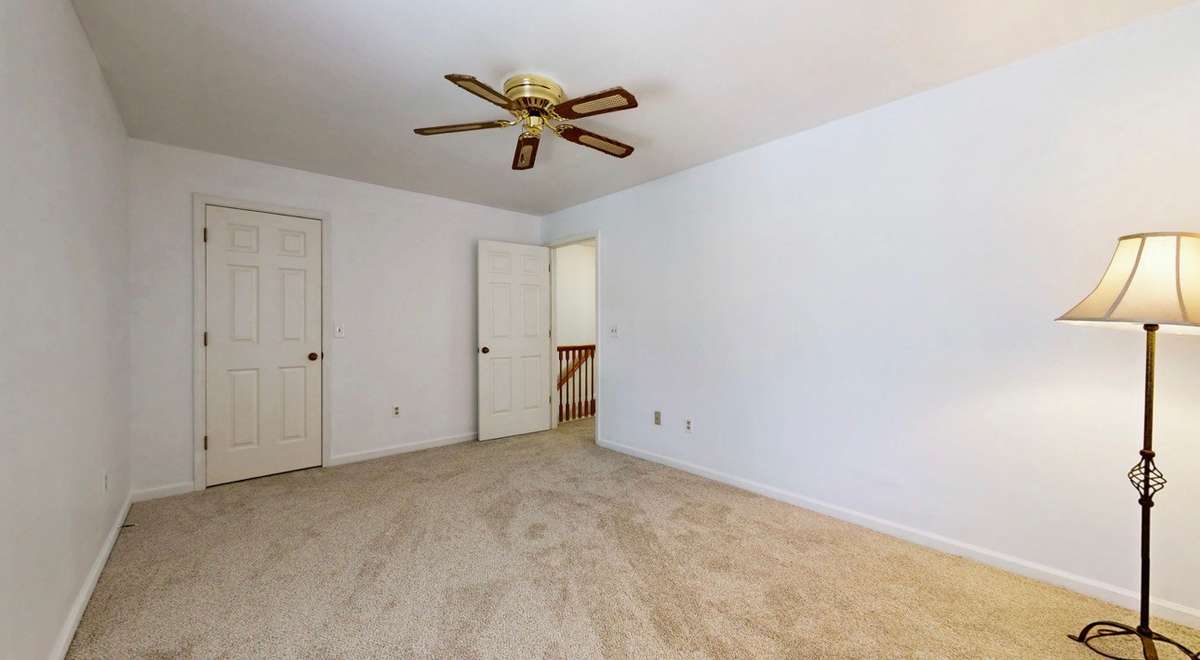 Guest bedroom with ceiling fan and new carpet.