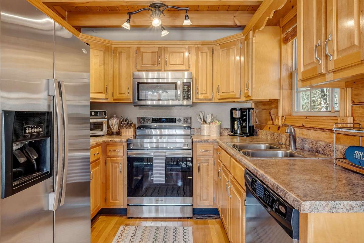 Stainless appliances compliment the natural wood finishes of the cabinetry, walls and flooring.