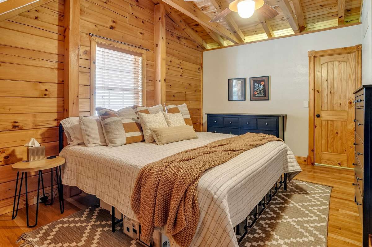 Upper Bedroom featuring a walk-in closet, exposed rafters, hardwood flooring and warm pine walls.