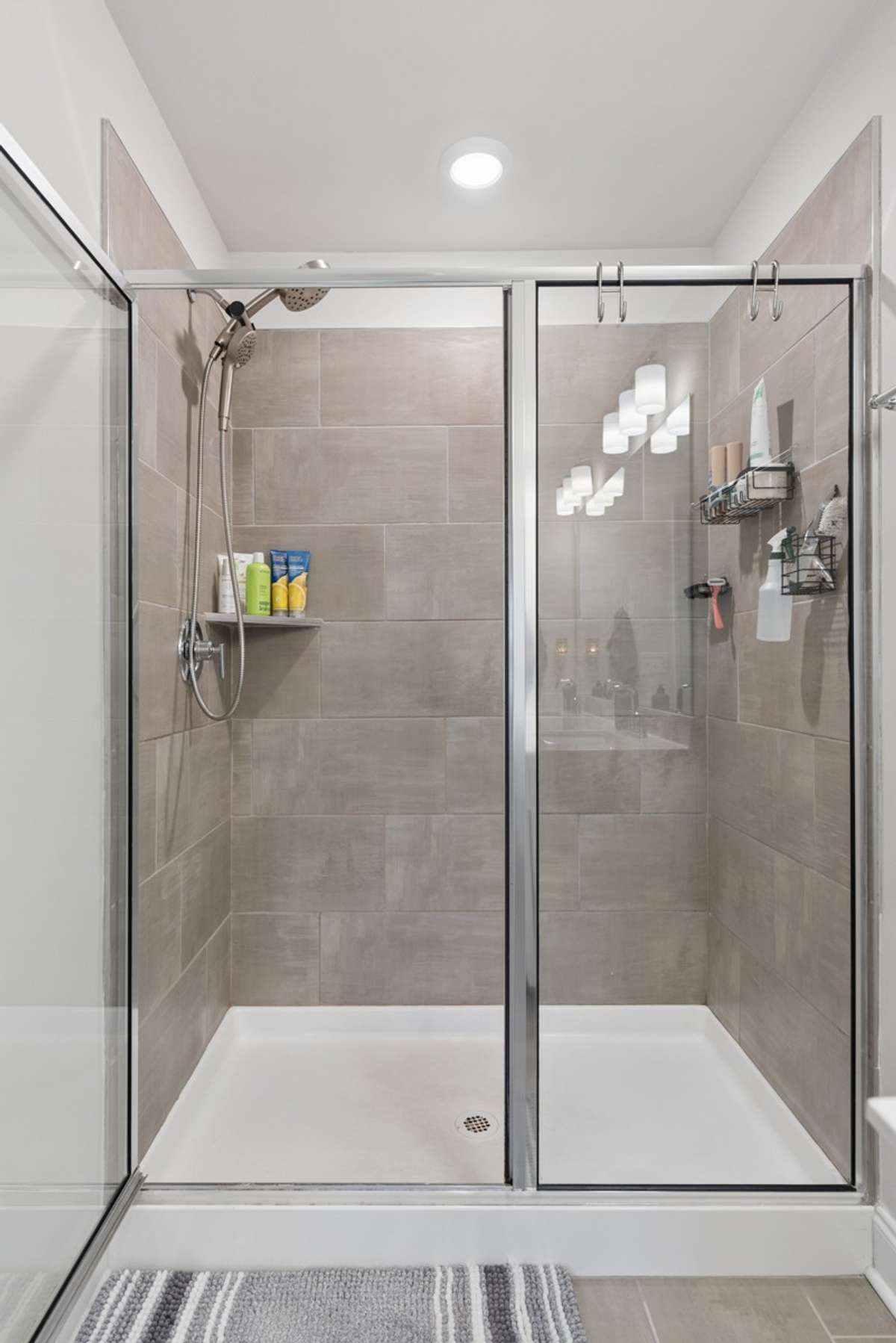 Stunning primary bathroom featuring a dual vanity with quartz countertops, walk-in tiled shower, private water closet, walk-in closet, and plenty of storage — upscale finishes and thoughtful design throughout.