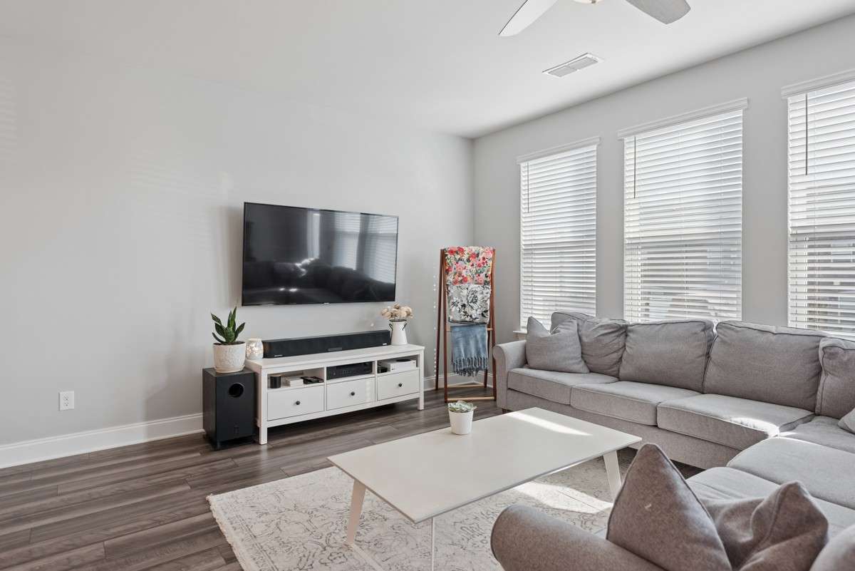 Bright, open, and generously sized — this living room features warm LVP floors, a wall of windows, and an easy flow to the rest of the main level. A great space to unwind or gather with guests. Door leads to private concrete patio for entertaining.