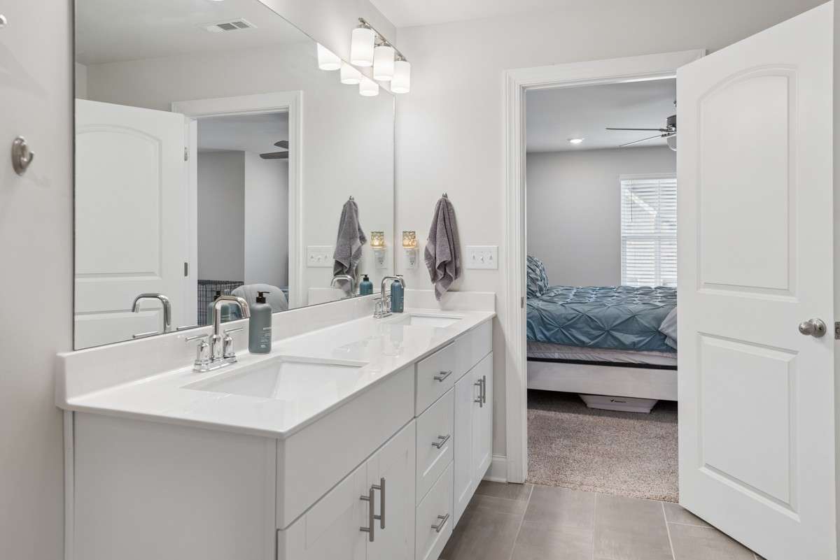 Stunning primary bathroom featuring a dual vanity with quartz countertops, walk-in tiled shower, private water closet, walk-in closet, and plenty of storage — upscale finishes and thoughtful design throughout.