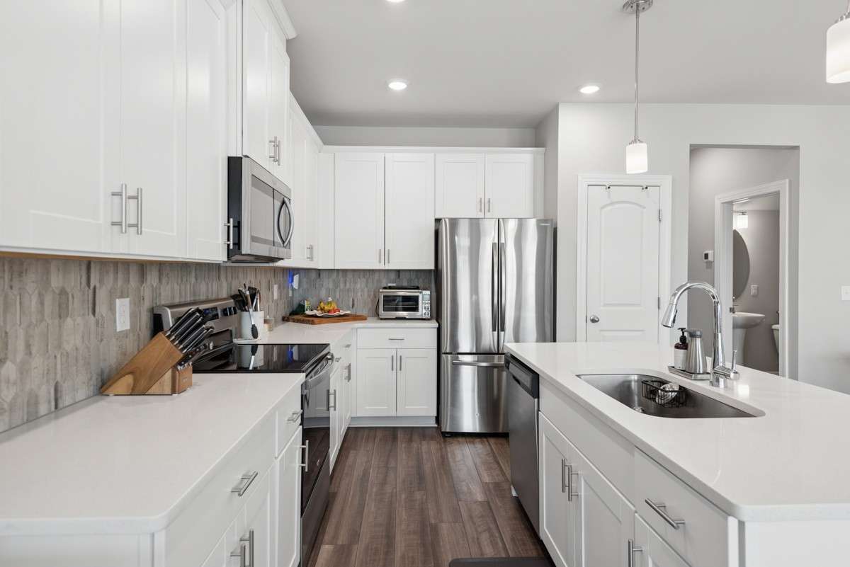 Open-concept living at its best — white shaker cabinets, quartz counters, stainless appliances, and a breakfast bar island that opens right into a sun-drenched living room & dining room. Warm, stylish, and move-in ready.