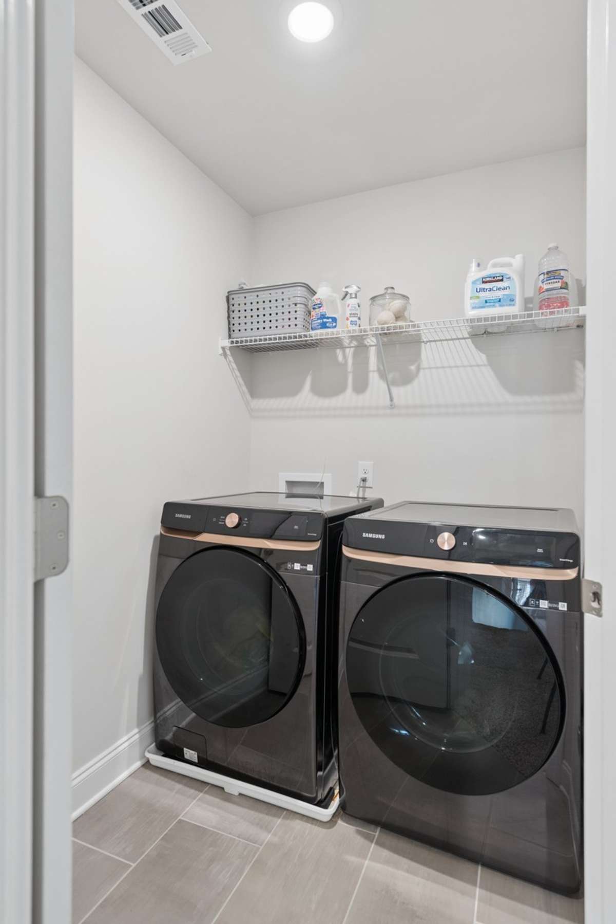 Dedicated laundry room with tile flooring, built-in shelving, and recessed lighting. Samsung front-load washer and dryer negotiable with an acceptable offer.