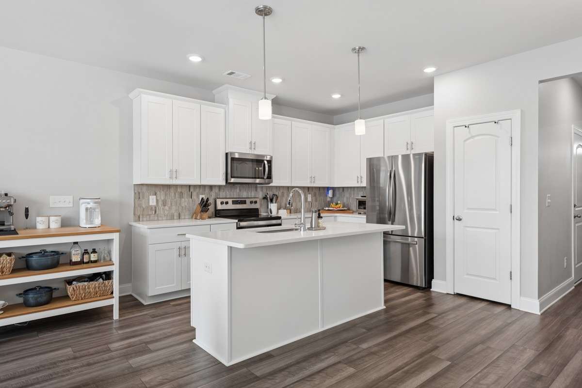 Open-concept living at its best — white shaker cabinets, quartz counters, stainless appliances, and a breakfast bar island that opens right into a sun-drenched living room & dining room. Warm, stylish, and move-in ready.