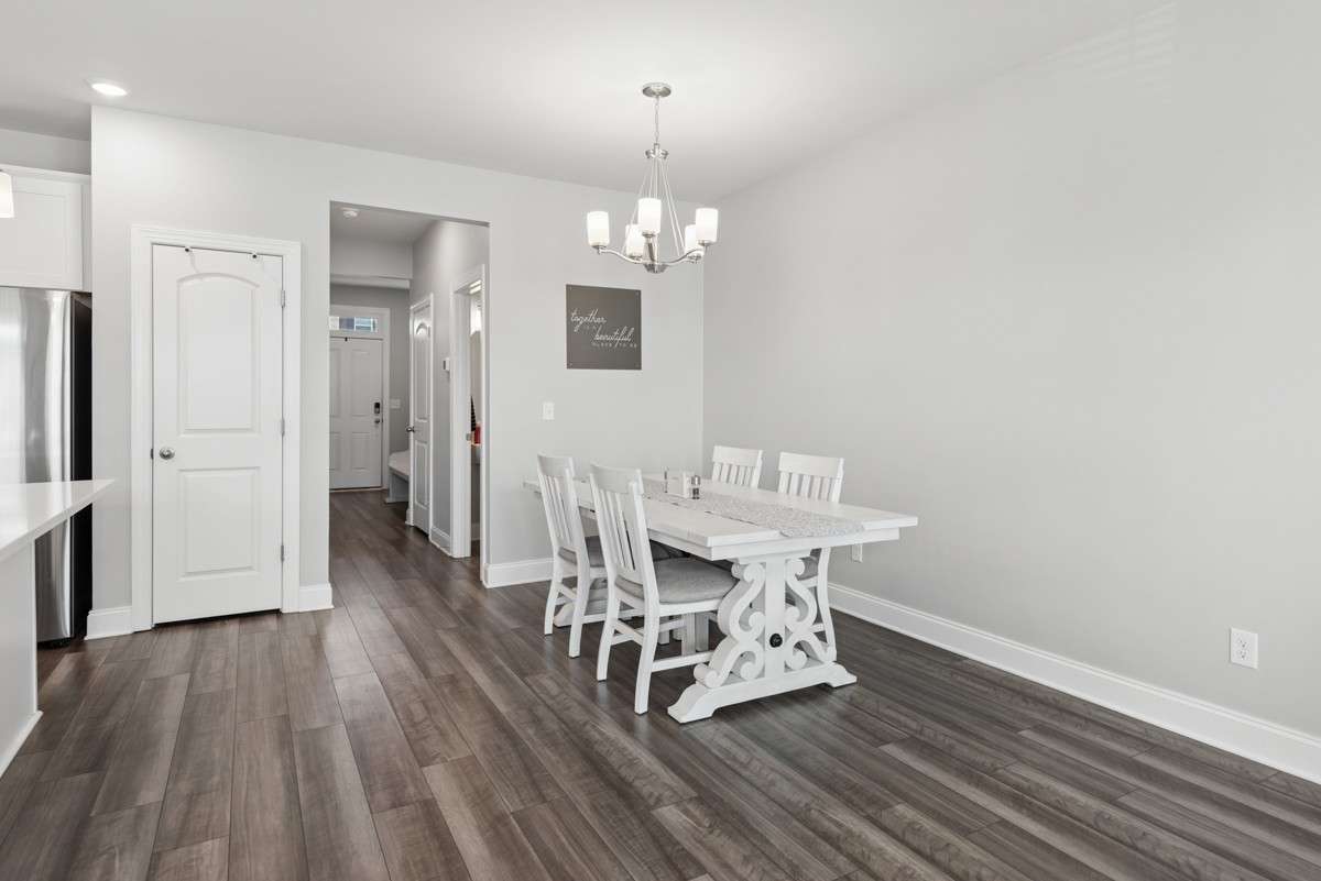 Gracious dining area with dark LVP floors, a classic chandelier, and an easy open flow to the kitchen — plenty of room for everyone to pull up a chair.