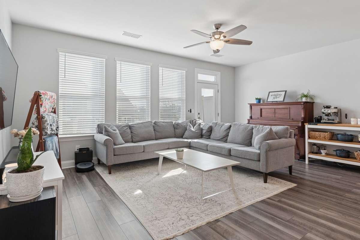 Bright, open, and generously sized — this living room features warm LVP floors, a wall of windows, and an easy flow to the rest of the main level. A great space to unwind or gather with guests. Door leads to private concrete patio for entertaining.