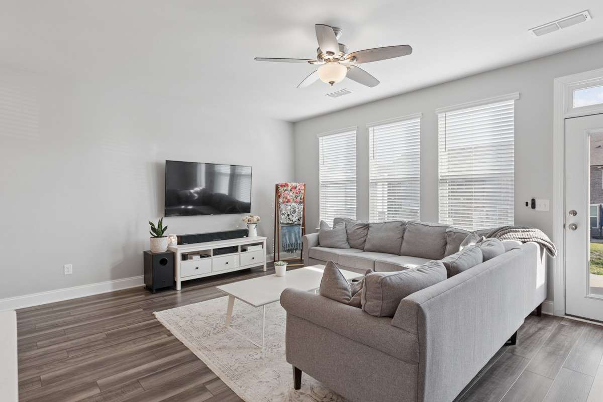Bright, open, and generously sized — this living room features warm LVP floors, a wall of windows, and an easy flow to the rest of the main level. A great space to unwind or gather with guests. Door leads to private concrete patio for entertaining.