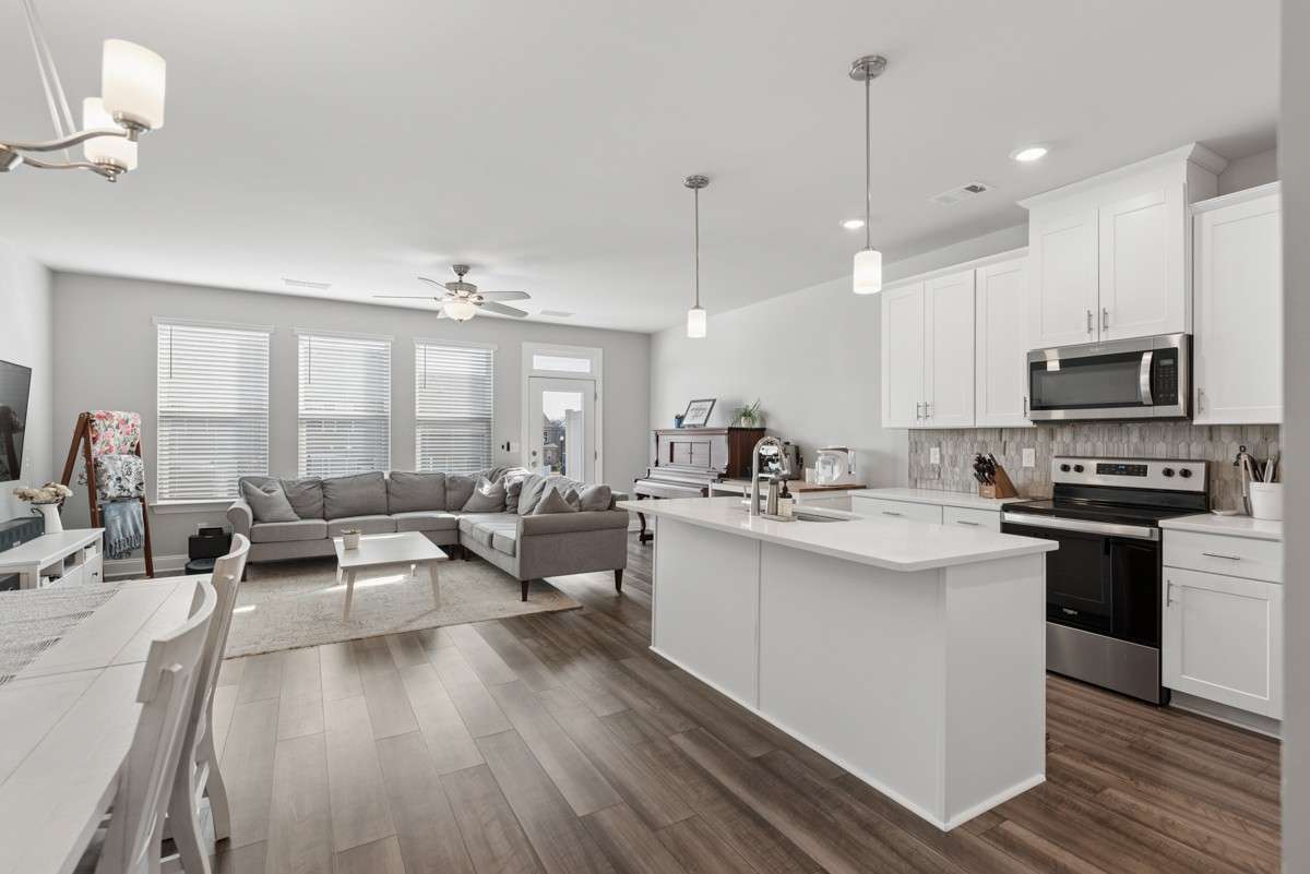 Open-concept living at its best — white shaker cabinets, quartz counters, stainless appliances, and a breakfast bar island that opens right into a sun-drenched living room & dining room. Warm, stylish, and move-in ready.