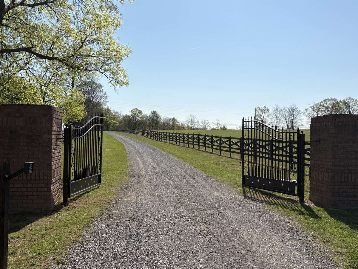 Gated Entrance leads down long driveway to house and barn.