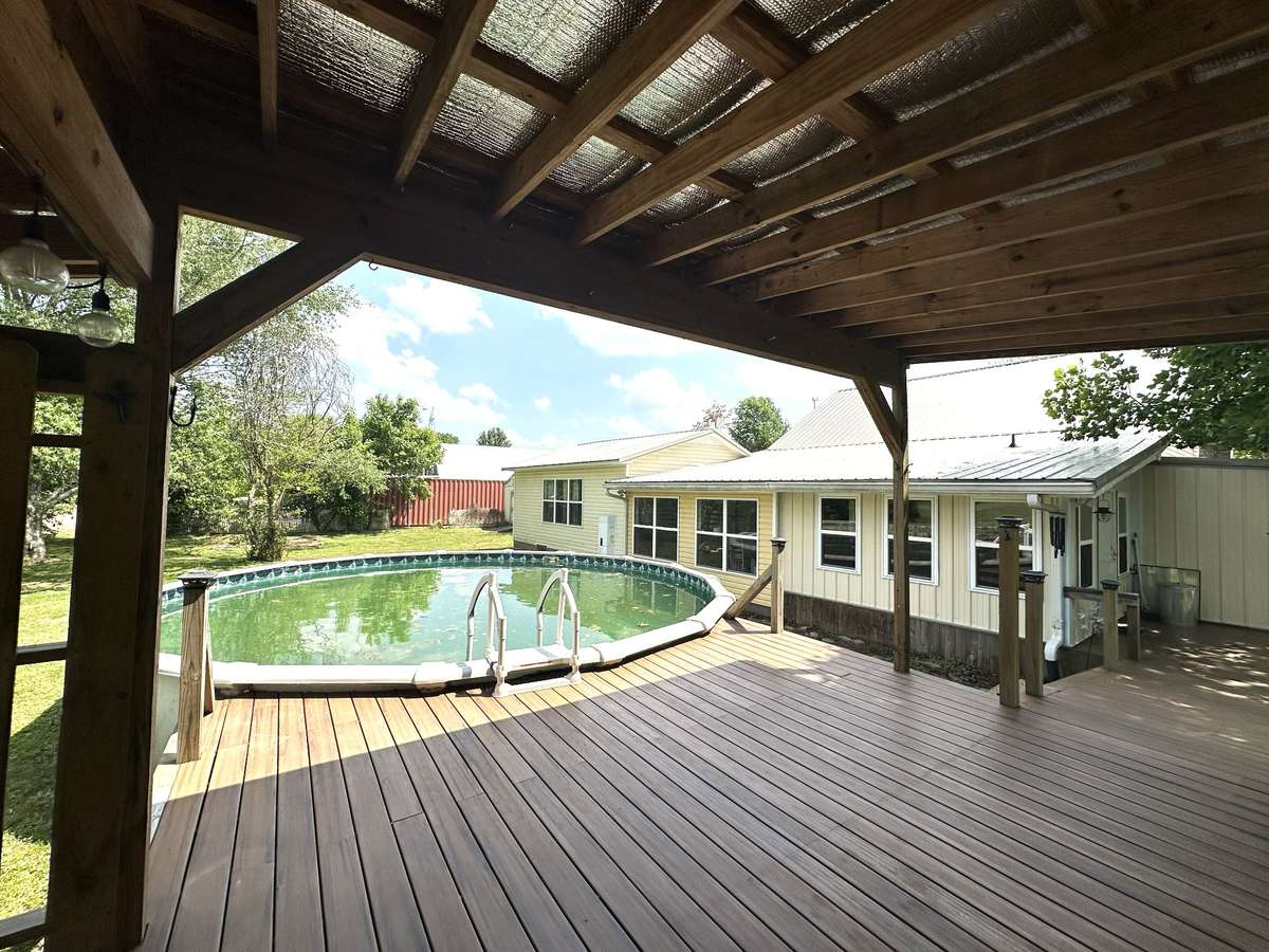 view of back of home with above ground pool and pool deck