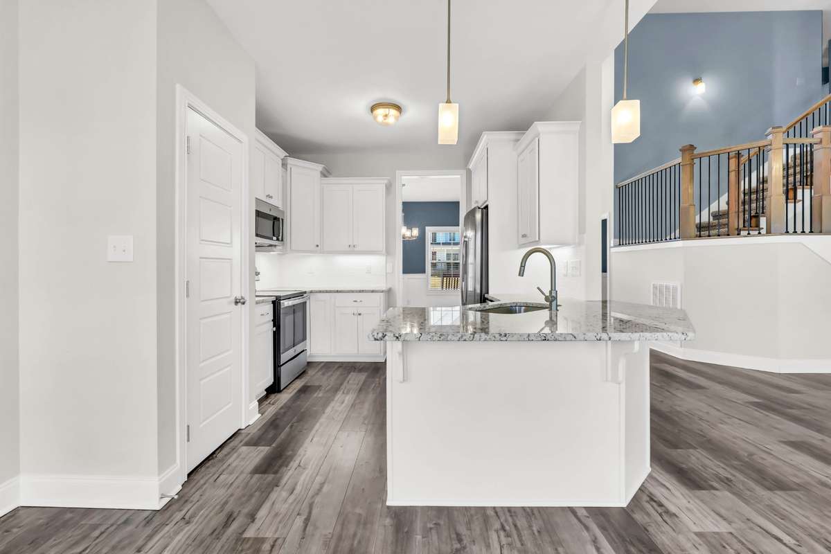 Crisp white cabinetry and stunning countertops create a clean, timeless look, complemented by stainless steel appliances and modern fixtures