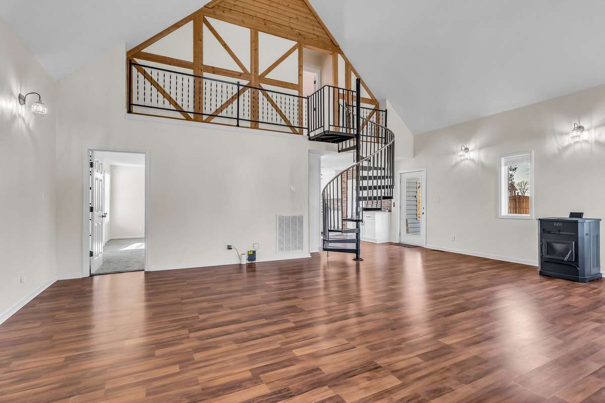Step into the large living room with soaring ceilings, pellet stove, and abundant natural light.
