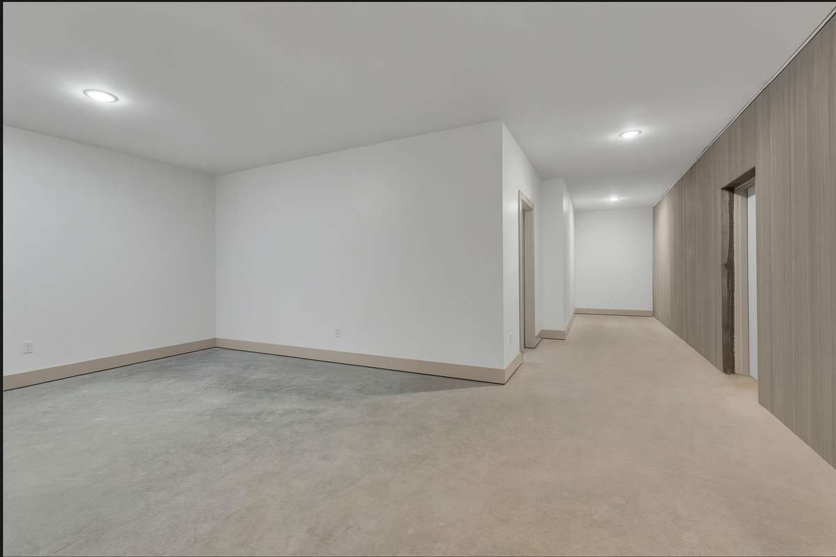 Photo shows the lower-level secure area with commercial-grade steel-door entry, fully finished interior and integrated tech infrastructure—ideal for a dedicated safe-room or command centre
