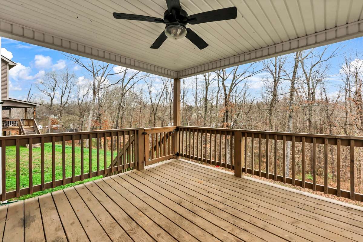Lovely covered back deck with ceiling fan looks out to a private yard with mature trees and no homes directly to the rear