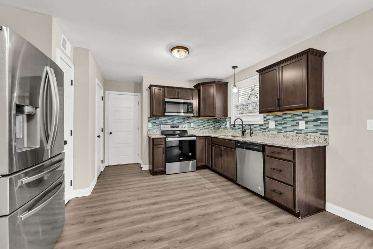 Big kitchen with granite counters, tile backsplash, stainless steel appliances, and pantry and half bath. Buyer may select flooring, which is on-site.