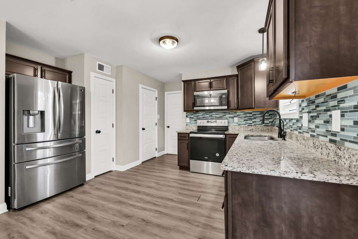 Big kitchen with granite counters, tile backsplash, stainless steel appliances, and pantry and half bath. Buyer may select flooring, which is on-site.
