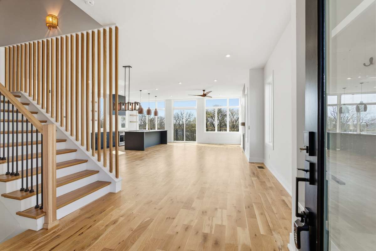 Expansive open-concept living with wide-plank white oak select hardwoods, designer lighting, and oversized windows, seamlessly blending kitchen, dining, and living into one elevated space.