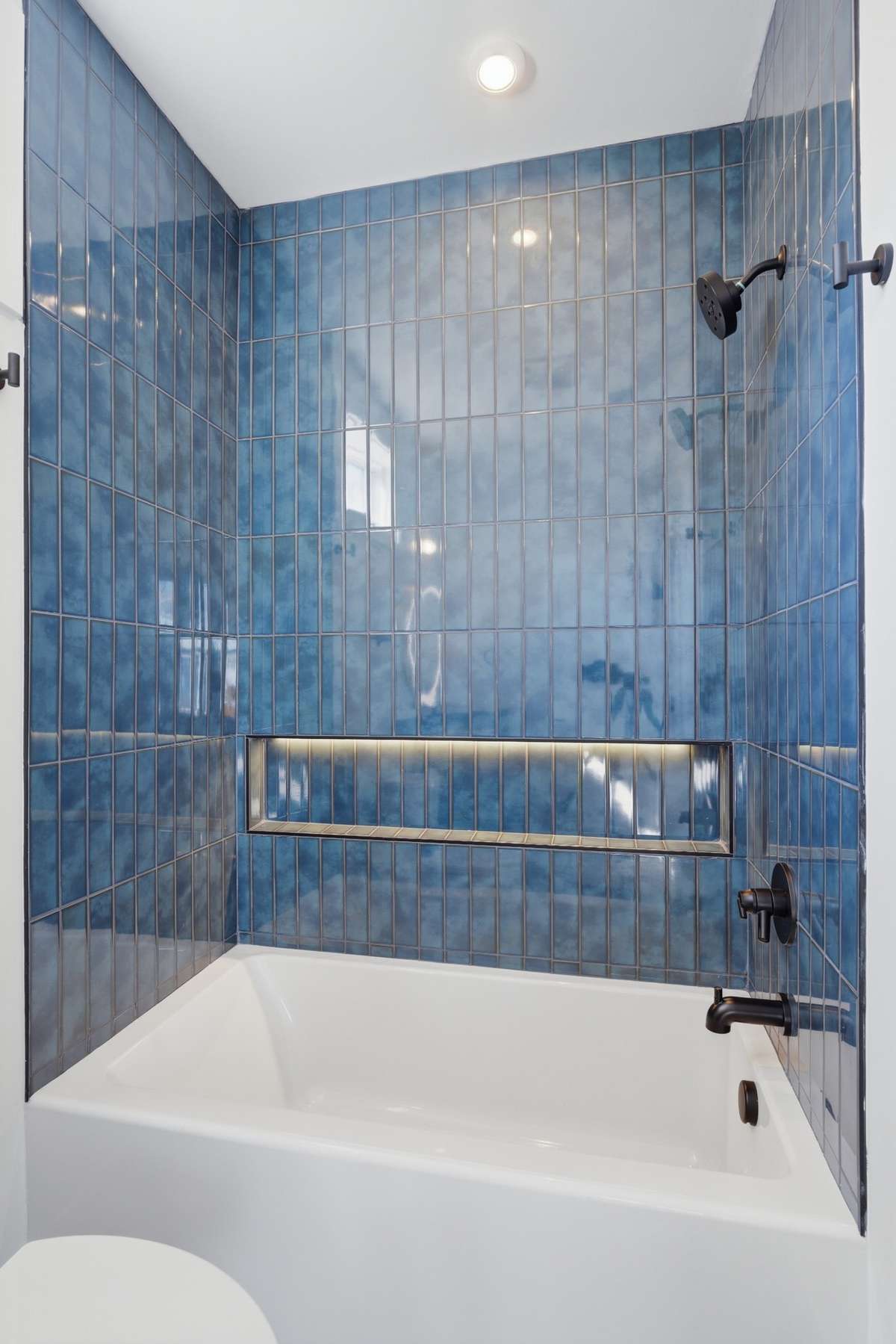 Bathroom 3: Bold, design-forward guest bath featuring rich blue designer tile and integrated lighting, a standout space that adds personality and depth to the home.