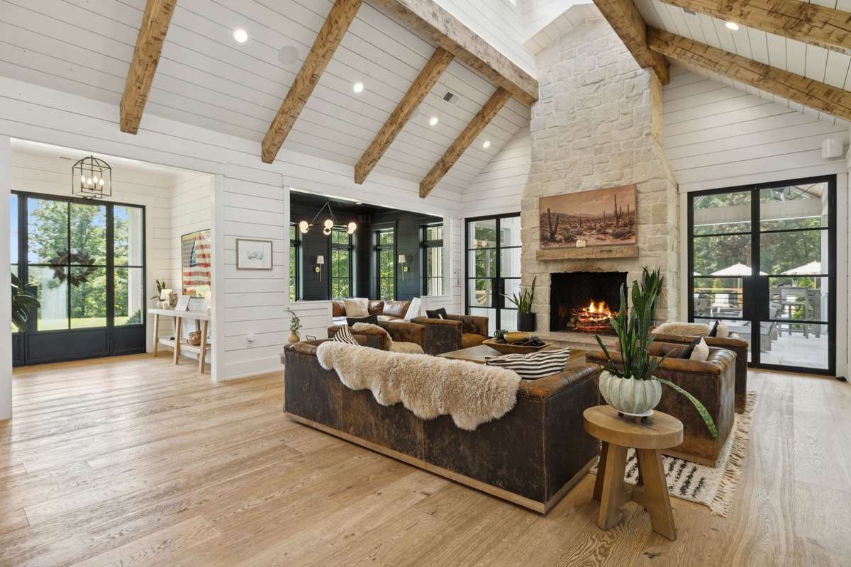 Beautiful Open Living Room with Large Fireplace, exposed beams, much natural light spilling into the space.