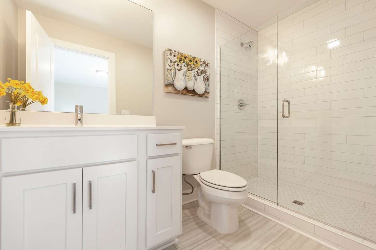 The primary suite has a tile shower with frameless glass door.