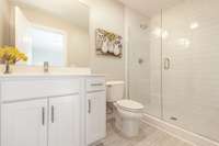 The primary suite has a tile shower with frameless glass door.