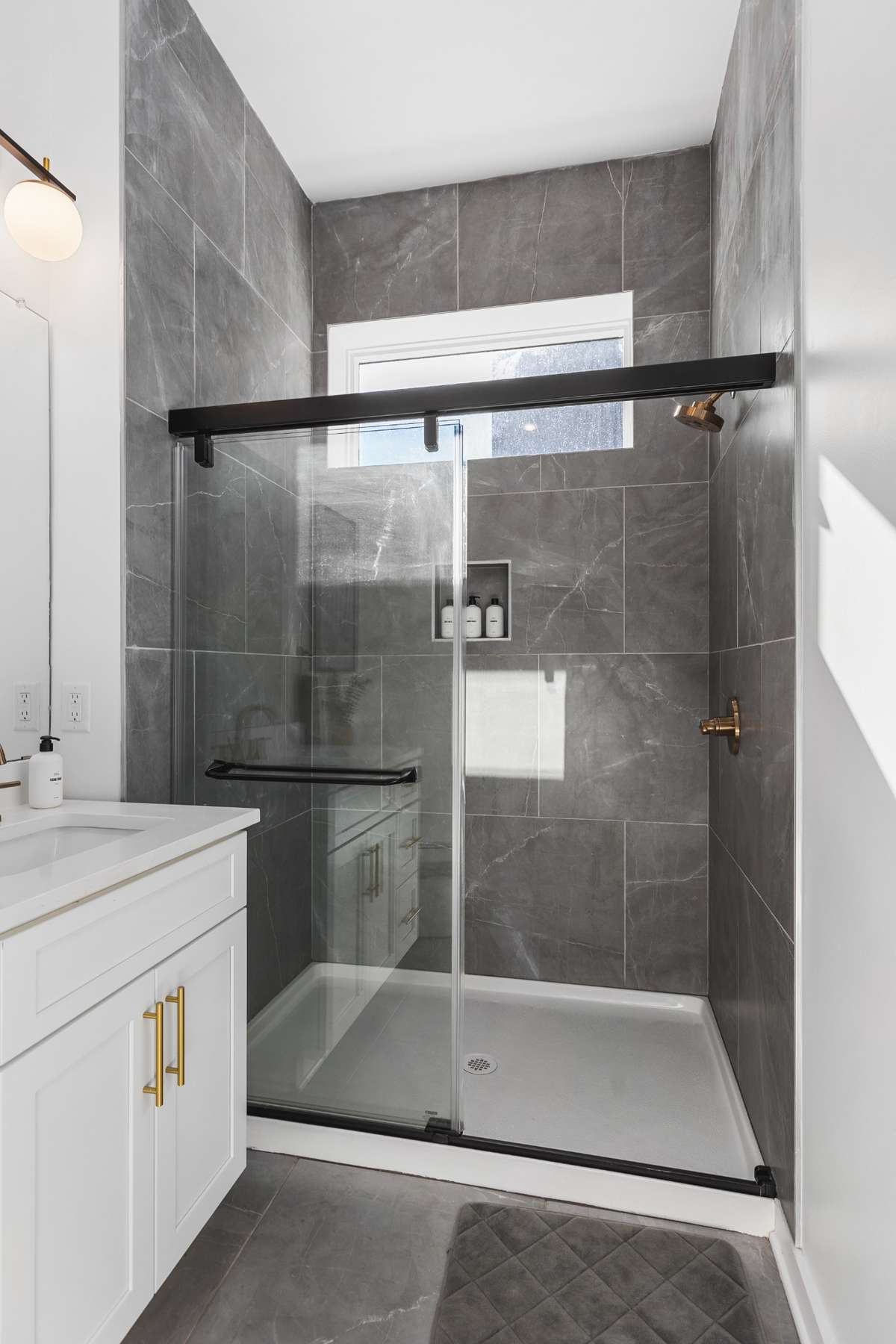 Primary suite features large walk-in shower with window to bring in sunlight