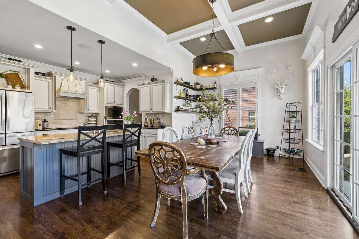 Breakfast/den area with coffered ceiling, chandelier and doors and windows overlooking pool and backyard
