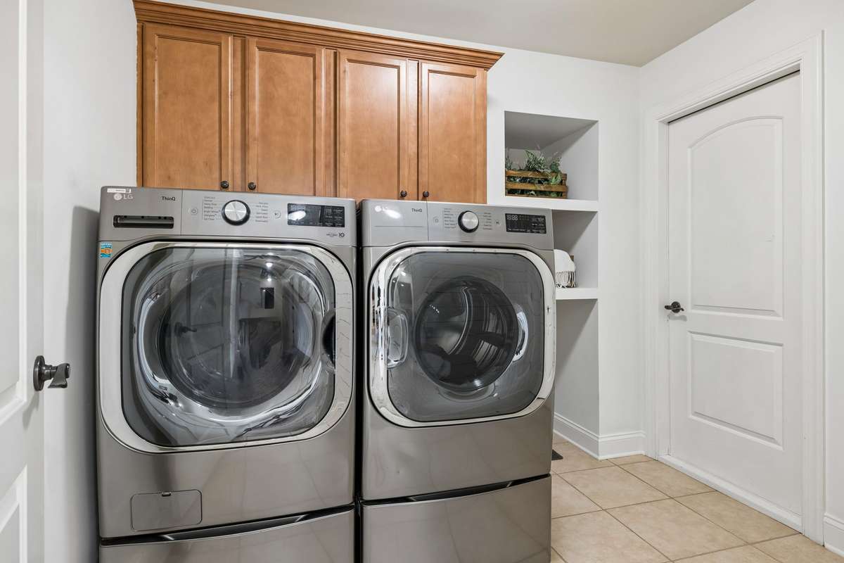 Laundry room with built-in cabinets and wall shelves - the door leads to attic area