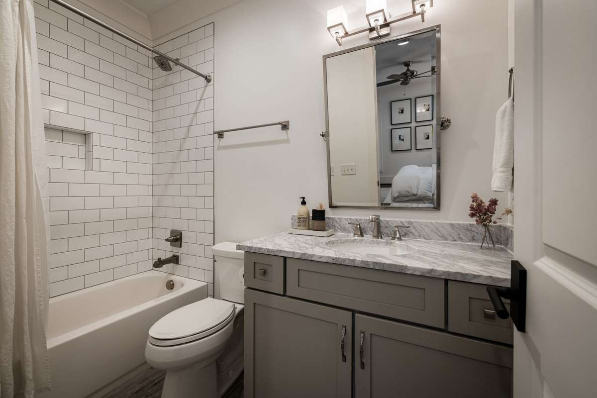 En suite bath with marble countertop and tub-shower combination